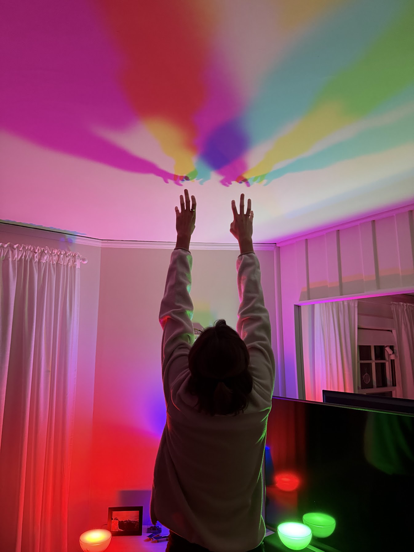 Gail reaching toward rainbow-colored light projections